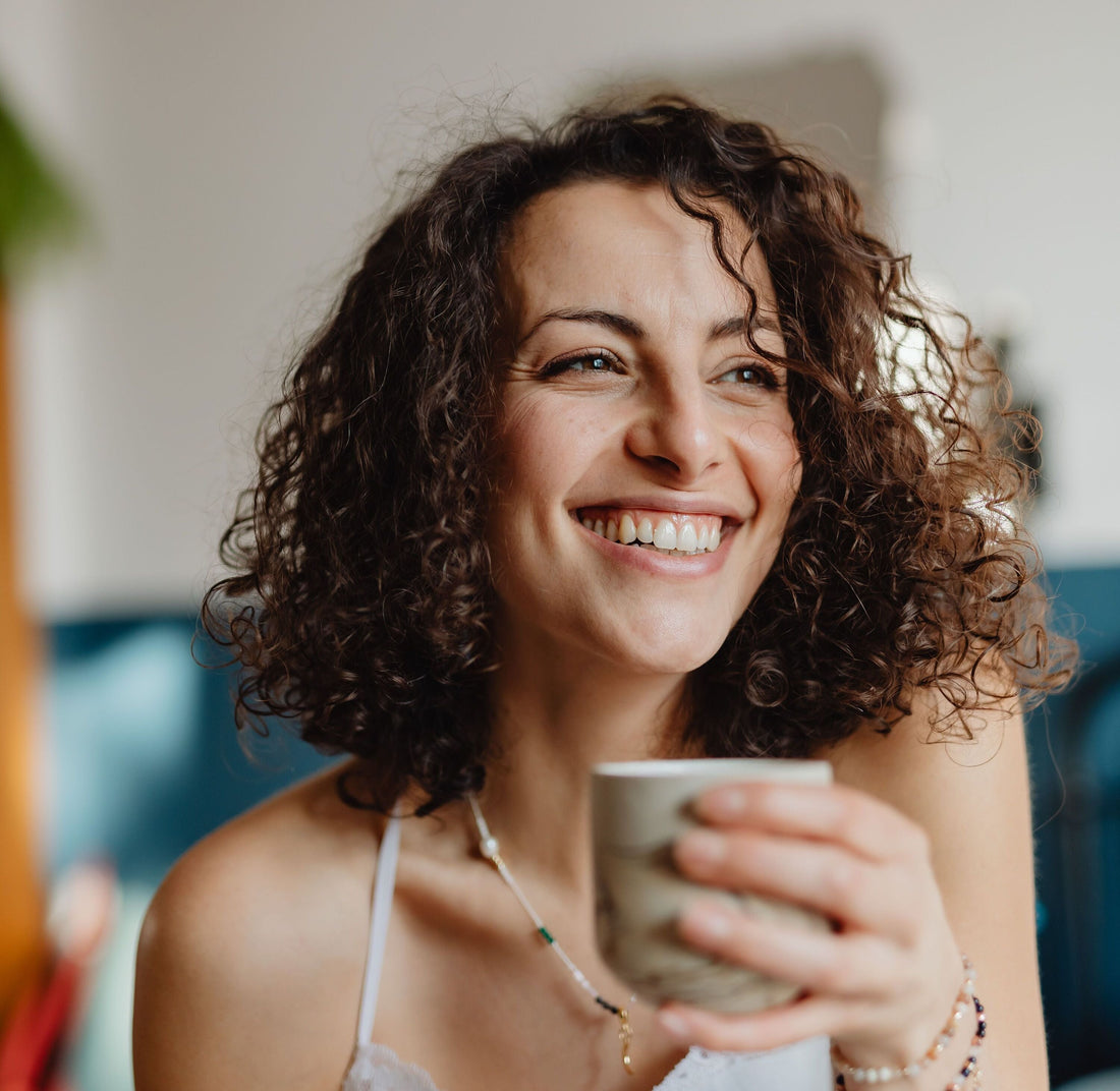 Persona disfrutando de una taza de café de especialidad en casa con una sonrisa