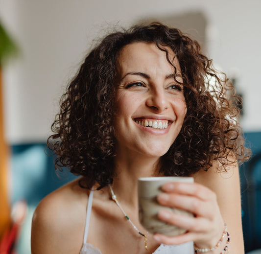 Persona disfrutando de una taza de café de especialidad en casa con una sonrisa